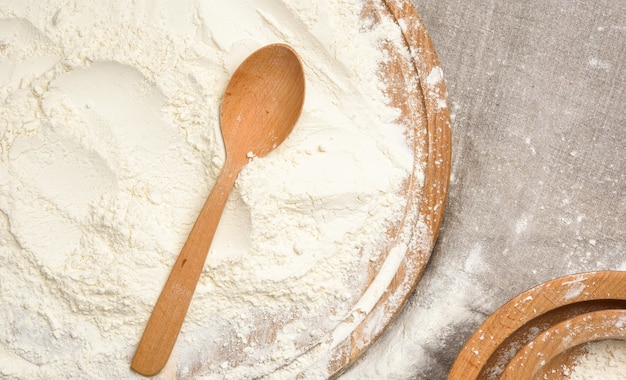 Foto farina di frumento bianco in un cucchiaio di legno, vista dall'alto, da vicino