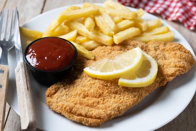 Wiener schnitzel with fried potatoes on wooden table