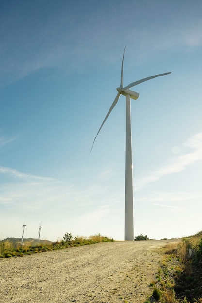 Wind turbines on hills generating electricity over a blue sky. Clean and ecological energy production concept.