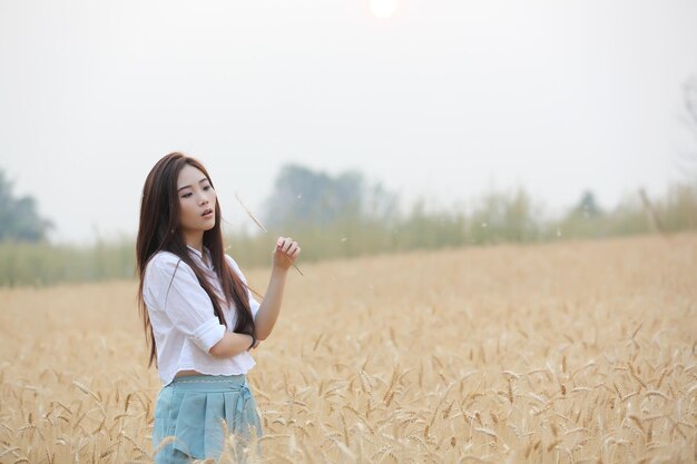 Photo woman blowing wheat crop while standing on field