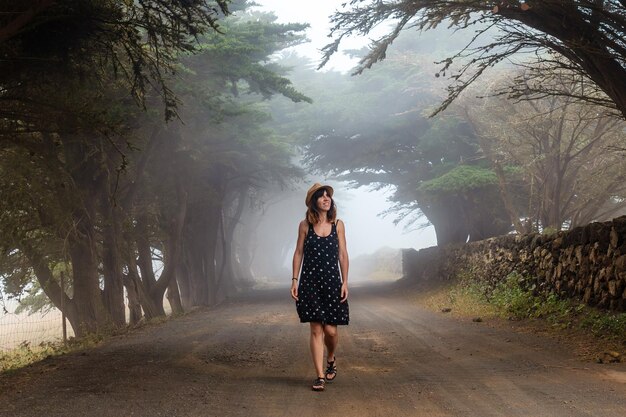 A woman enjoying walking through foggy trees towards the juniper forest in El Hierro Canary Islands