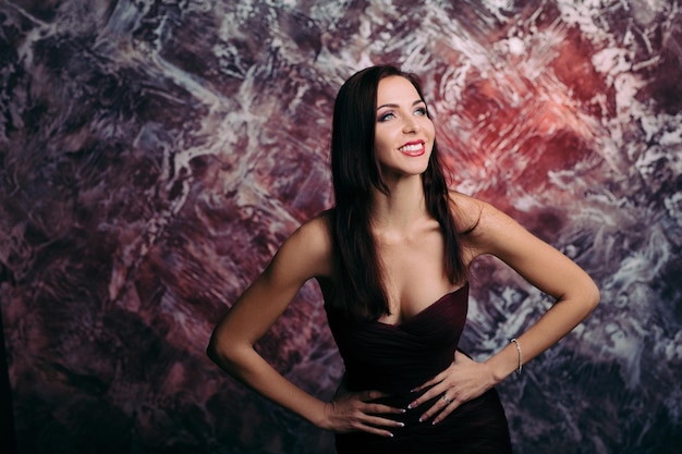 Woman in evening dress posing over dark background