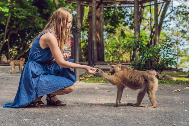 Woman feeds the monkey whith nuts