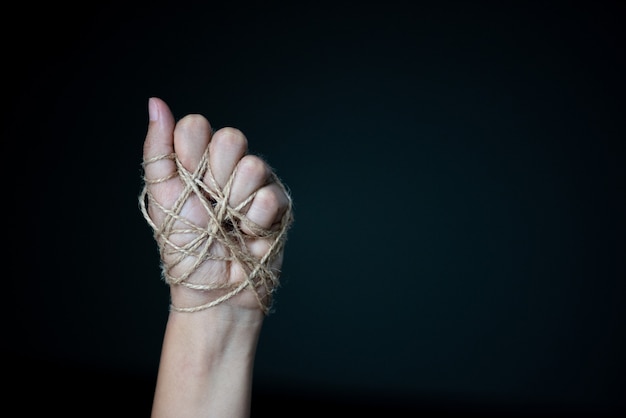 Photo woman hand tied with wire on dark background in low key, human rights day concept.