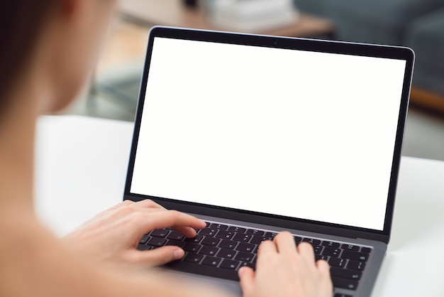 Woman hand using laptop and sitting on the table in the house, mock-up of a blank screen for the application.