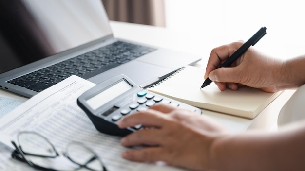 Woman is calculating annual tax monthly expenses with calculator and filling form of Individua Tax