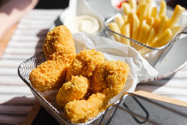 A woman in a restaurant or fast food cafe eats fried wings in air batter with different sauces and fries