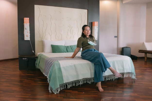 A woman sits on a bed in a room with a sign that says'the bed is made '