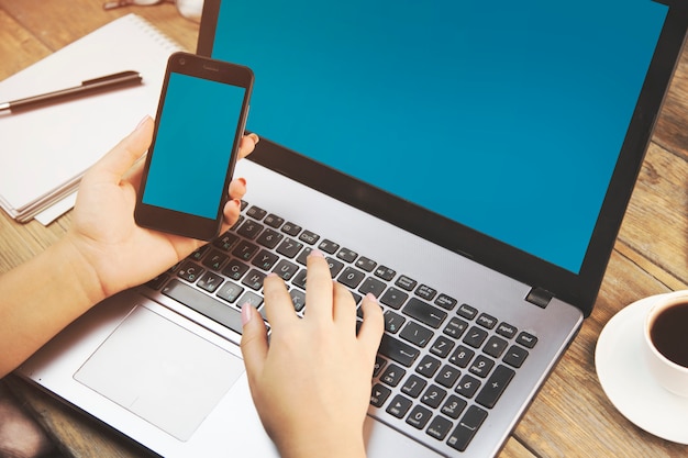 Photo woman working in computer with smartphone