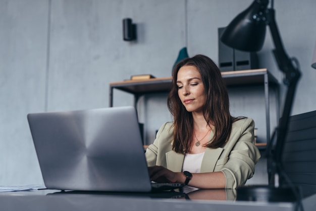 Woman works in her office sitting at her desk with a laptop