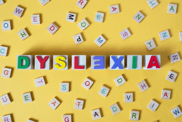 Photo wooden alphabet blocks with dyslexia word in the center on yellow background