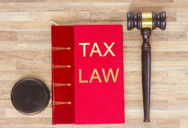 Wooden Law Gavel and red legal book on wooden table desktop top view