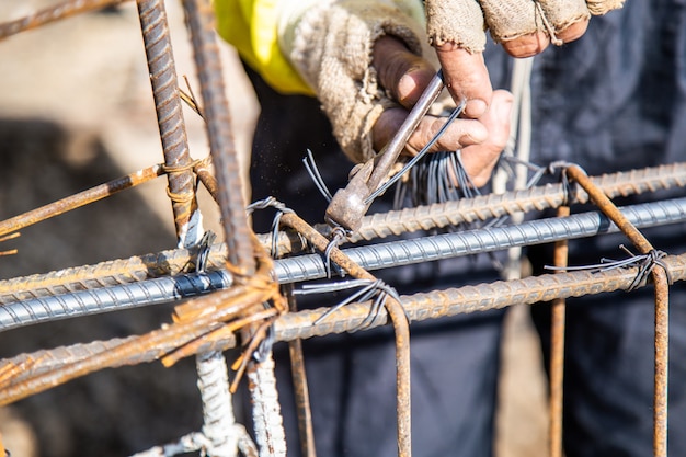 Worker are using wire and pliers to tie the rebar used for building foundations.