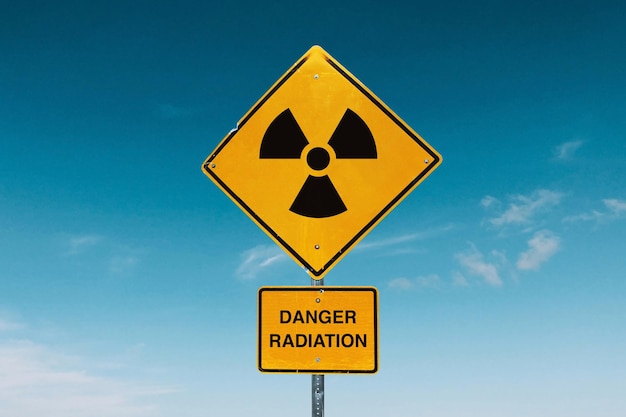 Yellow metal sign with radiation hazards against the blue sky Danger zone and radioactive contamination