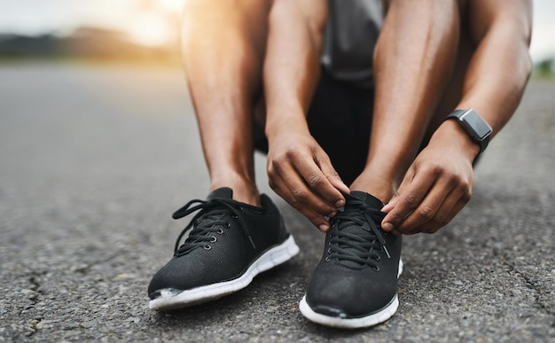 You cant afford to stumble Closeup shot of a sporty man tying his shoelaces while exercising outdoors