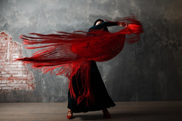 Photo young adult spanish woman dancing flamenco on gray vintage studio background