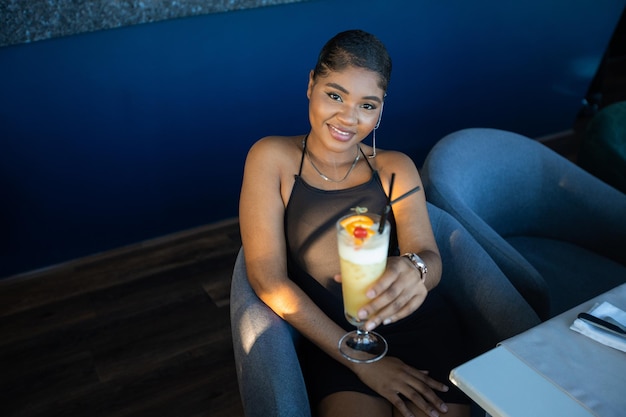 young african woman in a restaurant with a cocktail