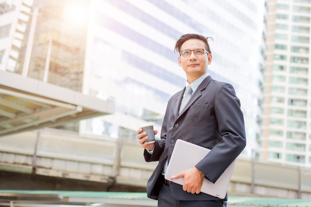 Photo young asia handsome businessman drinking hot coffee in the modern city. 