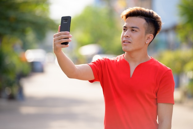 Young Asian man taking selfie in the streets outdoors