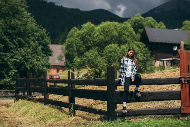 A young attractive Caucasian female sitting on a fence