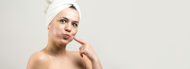 Young beautiful girl in a white towel on his head wears collagen gel patches under her eyes Mask under eyes treatment face