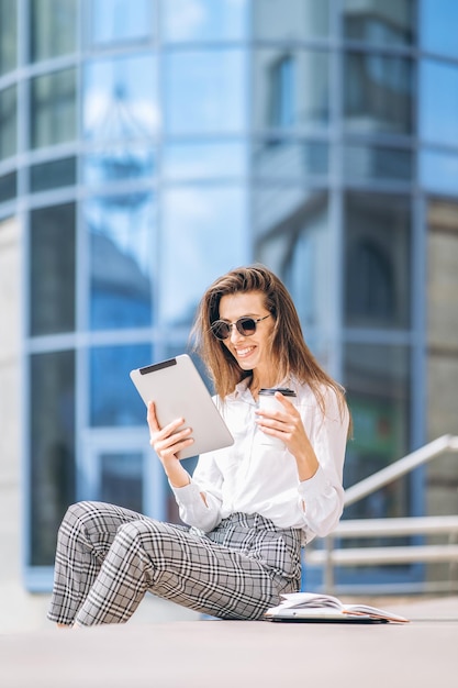 Young business lady working on the tablet outdoors near business center