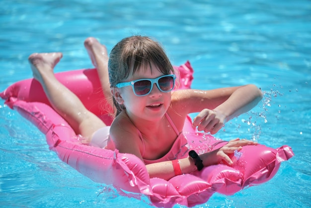 Young child girl falling in water from inflatable air mattress in swimming pool while swinnimg during tropical vacations Safety of aquatic activities concept