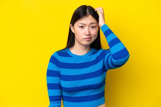 Photo young chinese woman isolated on yellow background with an expression of frustration and not understanding