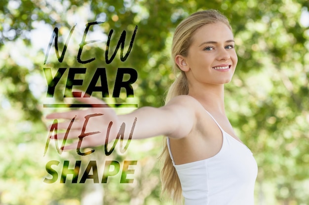 Young fit woman doing yoga in a park spreading her arms  against new year new shape