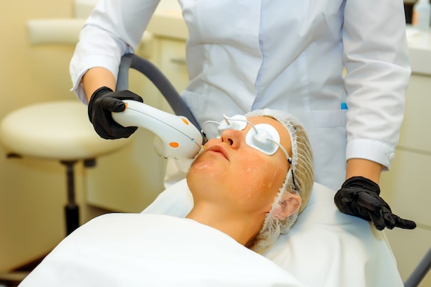 Young girl receives facial lifting therapy in beauty salon