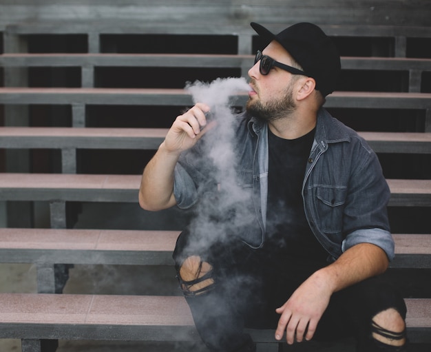 Photo young handsome man smoke with vape in urban location