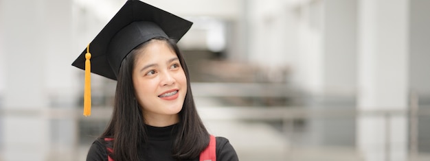 Photo young happy asian woman university graduate in graduation gown and cap in the college campus. education stock photo