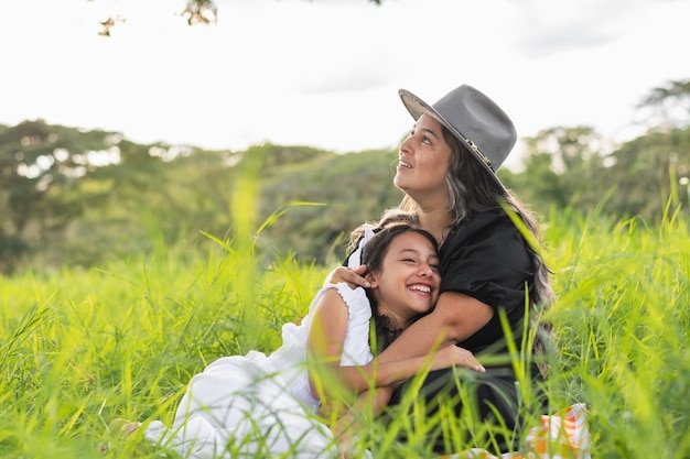 Photo young latin mother with her daughter lying on her chest looking up at the sky very happy