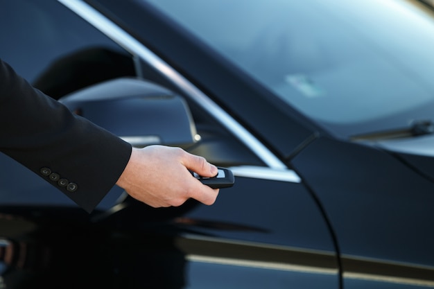 Young man opening his car door with the control remote key