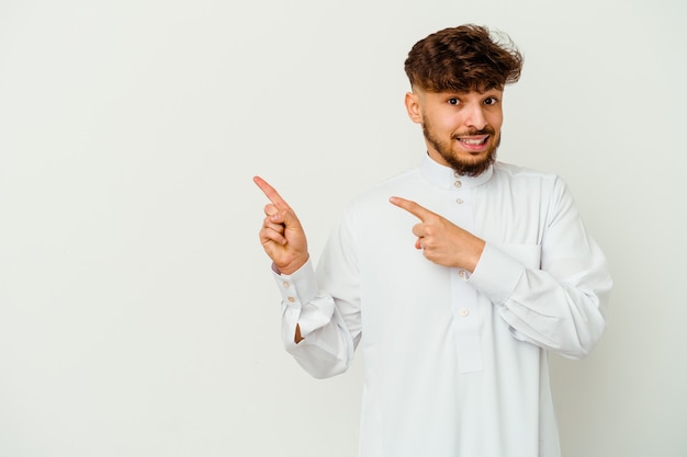 Young Moroccan man wearing a typical arab clothes isolated on white wall shocked pointing with index fingers to a copy space.