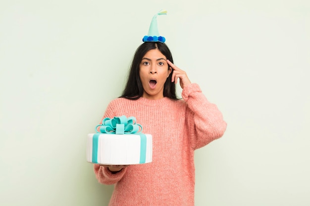 Photo young pretty hispanic woman looking surprised realizing a new thought idea or concept birthday cake concept