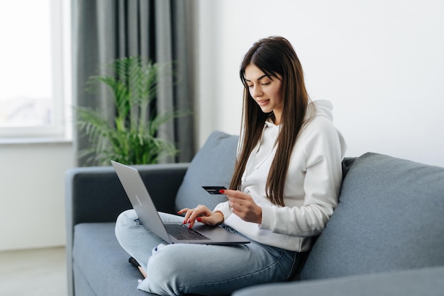 Young pretty woman working with laptop and credit card at home