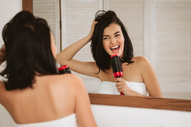 Young woman brushing healthy hair in front of a mirror