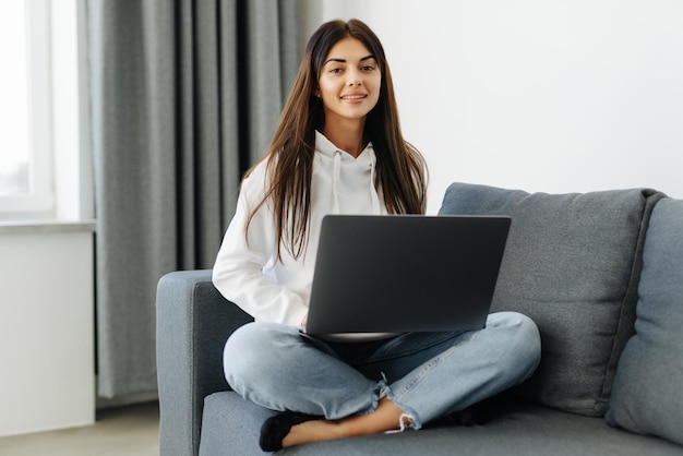 Young woman doing research work for her business Smiling woman sitting on sofa relaxing while browsing online shopping website