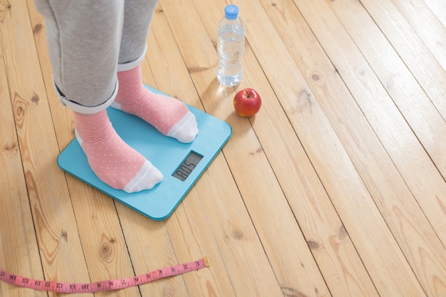 Photo young woman on electronic scales on  wooden floor