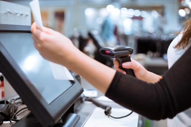 Photo young woman hands scaning / entering discount / sale on a receipt, touchscreen cash register, market / shop