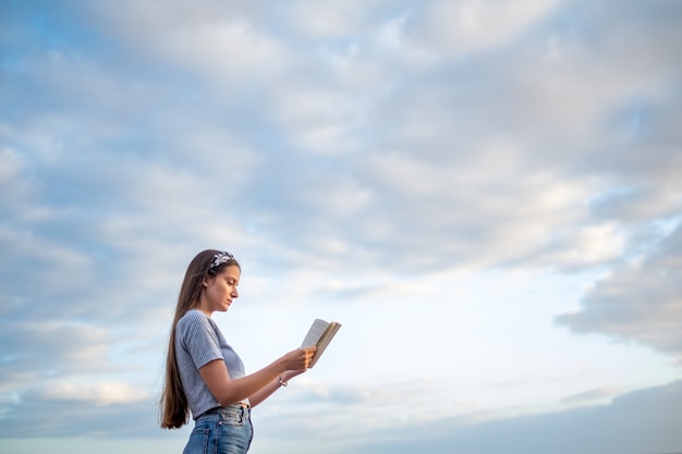 Young woman reading a book with blue sky