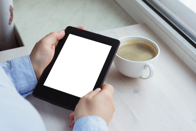 Photo young woman sitting by the window with an e-book