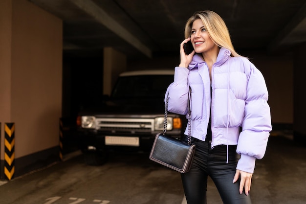 Young woman student walks along the city street and chats on the phone in spring