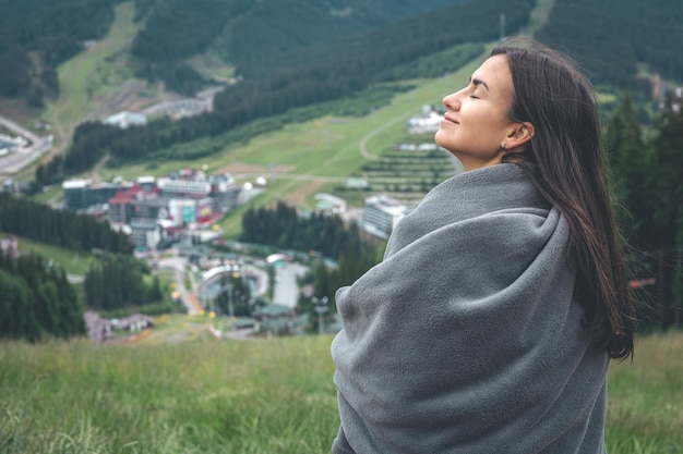 A young woman wrapped in a blanket in the mountains