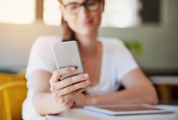 Youre never far from a wifi signal Shot of a relaxed young woman using her smartphone while chilling in her favorite cafe