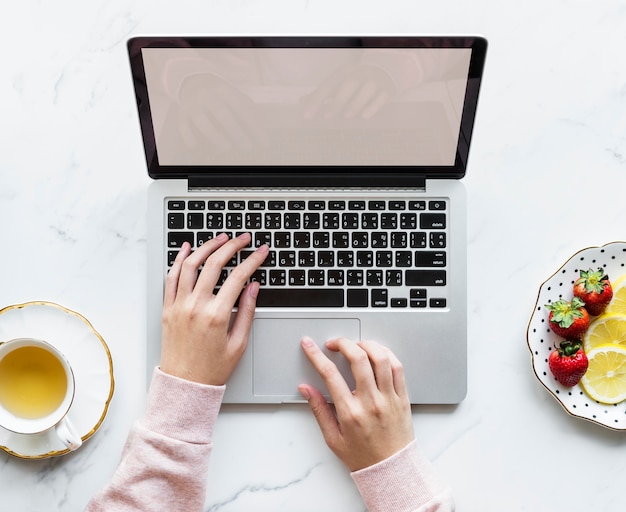 PSD aerial view of woman using a laptop on a marble table with design space