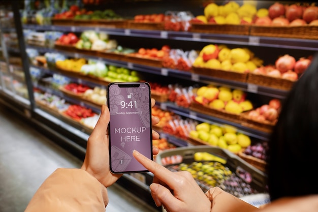 Hands holding smartphone in supermarket