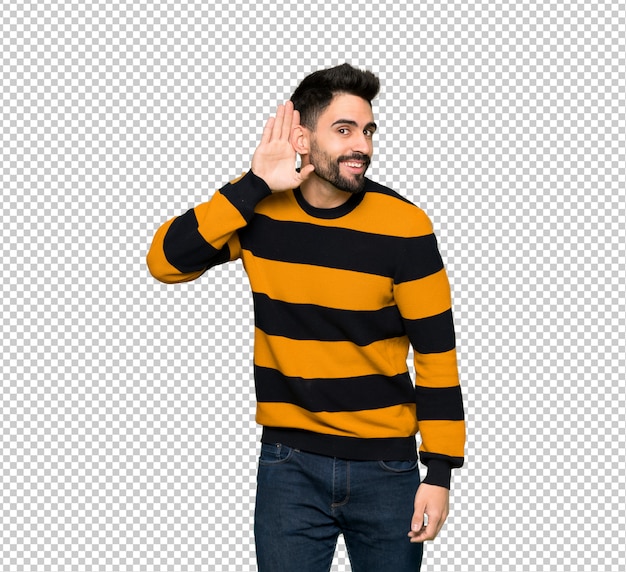 PSD handsome man with striped sweater listening to something by putting hand on the ear