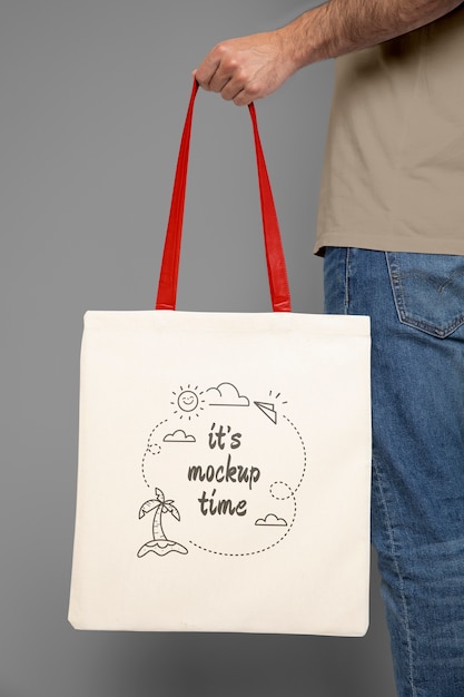 Man holding tote bag with grey background mockup